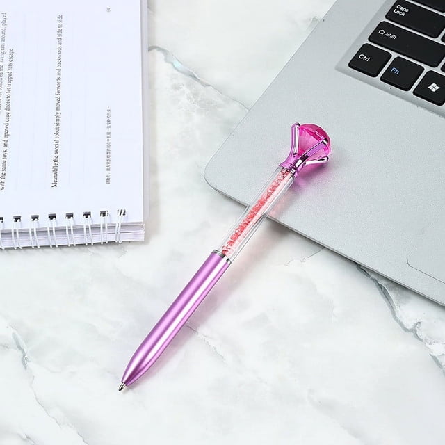 Stylo-bille à Diamant Cristal 1 ml, Instrument d'Écriture Rétractable Scintillant avec Encre gel à Pointe fine, Montré dans une Couleur Rose Vibrante avec un Baril Incrusté de Diamants et une Prise Ergonomique Confortable. le Stylo Présente un Mécanisme Rétractable et un Système de Flux d'Encre Fluide, Idéal pour le Journal, la Prise de Notes Ou l'Usage au Bureau. Affiché sur une surface en Marbre à Côté d'Un Portable et d'Un Cahier.