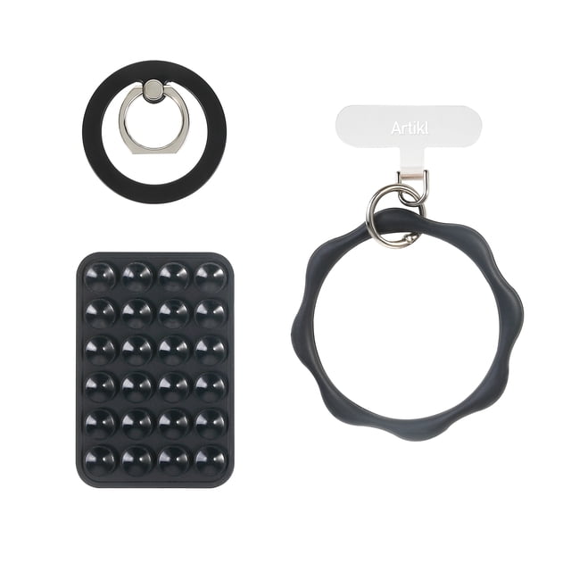 Artikl Universal MagSafe Compatible Accessory Bundle in black, featuring a circular foldable magnetic ring stand with silver metal ring for hands-free phone viewing, a rectangular black magnetic suction mount with suction cups for stable phone positioning, and a black silicone loop wristlet attached to a white clip labeled Artikl, compatible with MagSafe and most smartphones, also suitable for secure phone carry and display.
