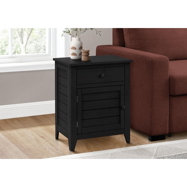 Monarch Specialties Accent Table, Nightstand, Storage Drawer, End, Side Table, Bedroom, Lamp, Storage, Black Veneer, Transitional style 25-inch high black veneer side table with a storage drawer and cabinet featuring clapboard paneling and black metal knobs, placed beside a brown sofa on light wood flooring near a window, topped with a decorative vase and candle, suitable as a nightstand or living room end table.