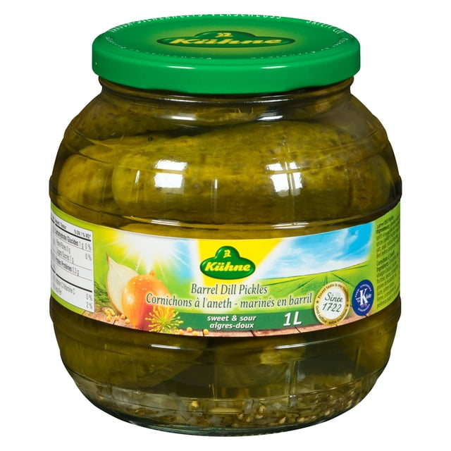 Kuhne Barrel Dill Pickles in a 1L clear glass jar with a green lid, containing whole crunchy pickles in traditional brine. The label features the Kuhne logo, onion and dill images, and states sweet and sour flavour ideal for sandwiches, burgers, and salads.