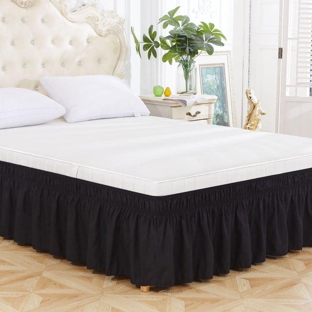 Bed Skirt Wrap Around with Elastic Ruffles, King Size Pleated Design featuring a deep 20-inch drop length, neat 4-inch ruffled trim, and easy elastic installation. The black bed skirt is shown installed on a king-size mattress in a bright, elegant bedroom setting with decorative furniture and plants.