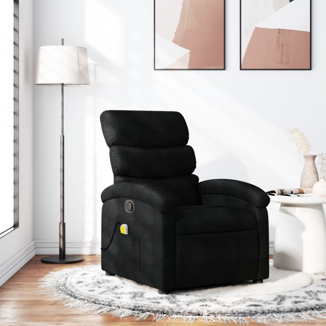 vidaXL Massage Recliner Chair in black fabric placed in a modern living room setting. The chair features a thickly padded seat, backrest, and wide armrests for comfort. It includes a manual reclining function with a handle on the right side, allowing adjustment of the footrest and backrest up to 135 degrees. The chair also offers a 6-point vibration massage function powered by a USB connector, with a side pocket for convenient storage of the remote control. The frame is made of wood and metal for stability, and the fabric is breathable and durable. Dimensions are 70 x 92 x 99.5 cm when upright and 70 x 147 x 80 cm when reclined. Assembly is required.
