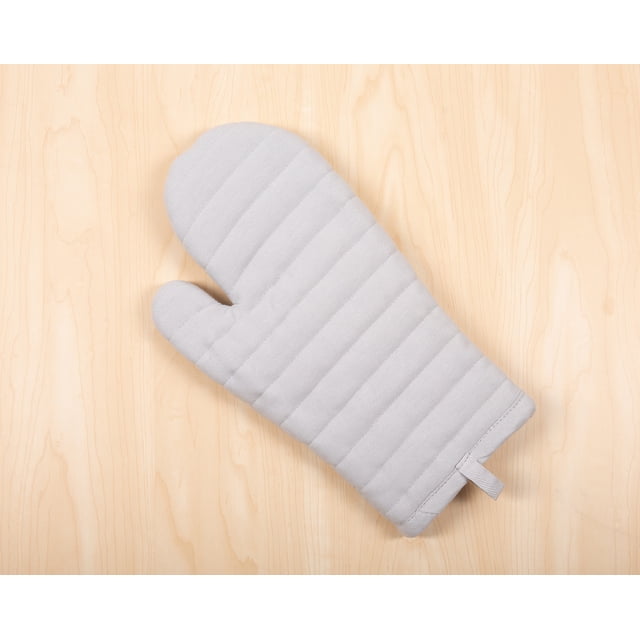 Mainstays Oven Mitt in gray, 7” x 12.5”, with a quilted stripe pattern on an Oeko-Tex certified 100% cotton shell and 100% polyester fill, heat resistant and featuring a hanging loop, shown flat on a light wood surface. It is also suitable for handling hot cookware safely.