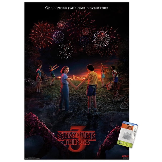 Netflix Stranger Things: Season 3 - Key Art Wall Poster, 22.375" x 34" framed, depicting six children on a grassy hill at night watching red and white fireworks over a glowing town, two children hold hands in the center, the Stranger Things 3 logo glows red at the bottom with dark twisted tree branches framing the scene, ideal for wall decor in bedrooms, living rooms, or offices.
