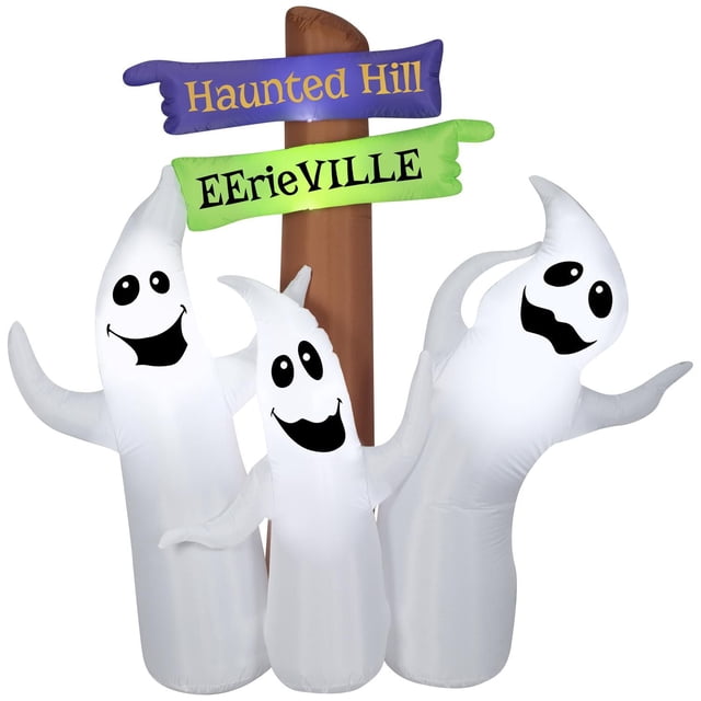 Halloween Inflatable Ghost Trio with Signs featuring three white Airblown® ghosts with smiling black faces in front of a brown post with purple and green directional signs reading 'Haunted Hill' and 'Eerieville'. This outdoor Halloween decoration lights up with energy-efficient LEDs and self-inflates for easy setup.