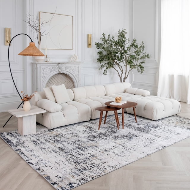 White beige Rug Branch Atlas Classic indoor area rug in a modern living room featuring a cream tufted sectional sofa, wooden nesting coffee tables, and decorative fireplace.