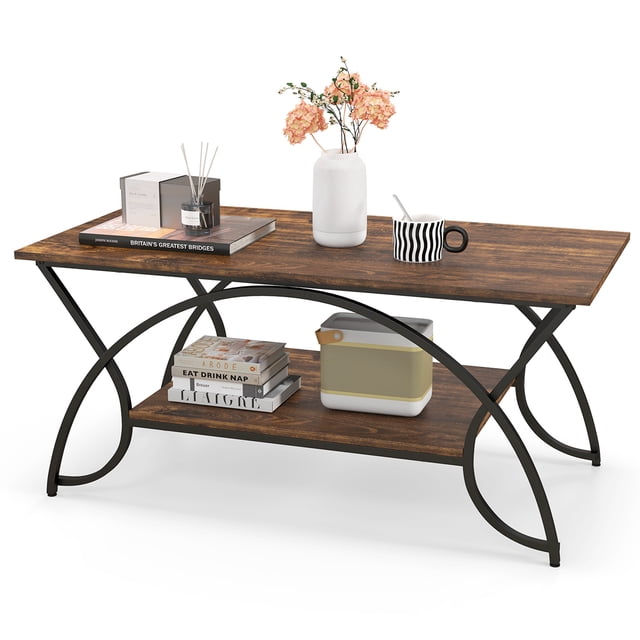 Costway Table Basse Industrielle à 2 Niveaux Table de Cocktail Rectangulaire avec Tablette de Rangement en Brun Rustique. la Table Présente un Plateau Spacieux à Fini grain de Bois Soutenu par un Cadre Métallique Arqué Robuste Noir Mat. sous le Plateau Se Trouvent une Tablette Secondaire pour un Rangement Supplémentaire, Tenant des Articles comme des Livres et de la Déco. la Table Est Conçue avec un vase, des Livres et une Tasse, Mettant en Valeur Sa Fonctionnalité et Son Attrait Esthétique. Conçue avec des Patins de Pieds Ajustables pour la Stabilité et un Dégagement de 6 Pouces pour un Nettoyage Facile avec un robot Aspirateur.