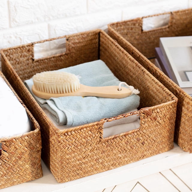 Panier de Rangement en Tressage d'Herbe de Mer pour Toilette, Garde-Manger et Cuisine, Taille M. Le Panier Rectangulaire Présente un design à Tissage Serré avec un Cadre en Métal pour la Durabilité et des Poignées des Deux Côtés pour un Transport Facile. Il Est Montré Tenant une Serviette Pliée et une Brosse en Bois, Placé sur une surface Blanche à Côté de Paniers Similaires.