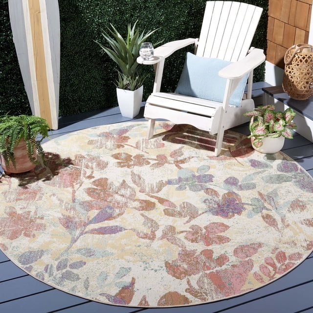 SAFAVIEH Barbados Andy Floral Tapis d'Intérieur/extérieur pour Aire Présente une Forme Ronde avec un Motif Floral pastel en Rose, Violet, beige et Vert sur une Terrasse Extérieure en Bois Grise. Il s'Agence avec une Chaise Adirondack Blanche avec un Coussin Bleu et des Plantes en Pot, Idéal pour une Déco de patio durable.