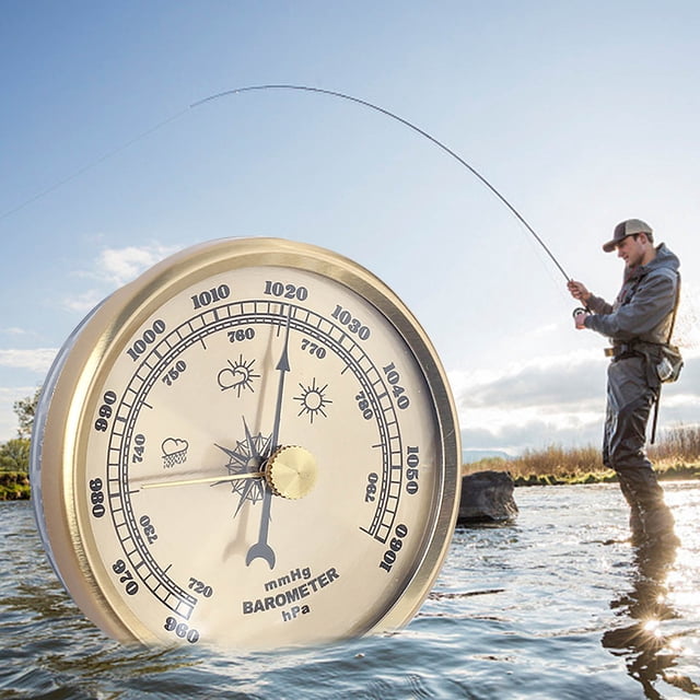 Atmospheric Pressure Barometer with 3-in-1 functionality as a manometer, hygrometer, and thermometer. The device features a sleek, gold-toned design with clear markings for atmospheric pressure, humidity, and temperature readings. Positioned in the foreground, the barometer is shown against an outdoor setting with a person fishing in a serene water body, emphasizing its use for weather monitoring during outdoor activities. Made from durable materials, it is suitable for home or office decor and practical for weather enthusiasts.