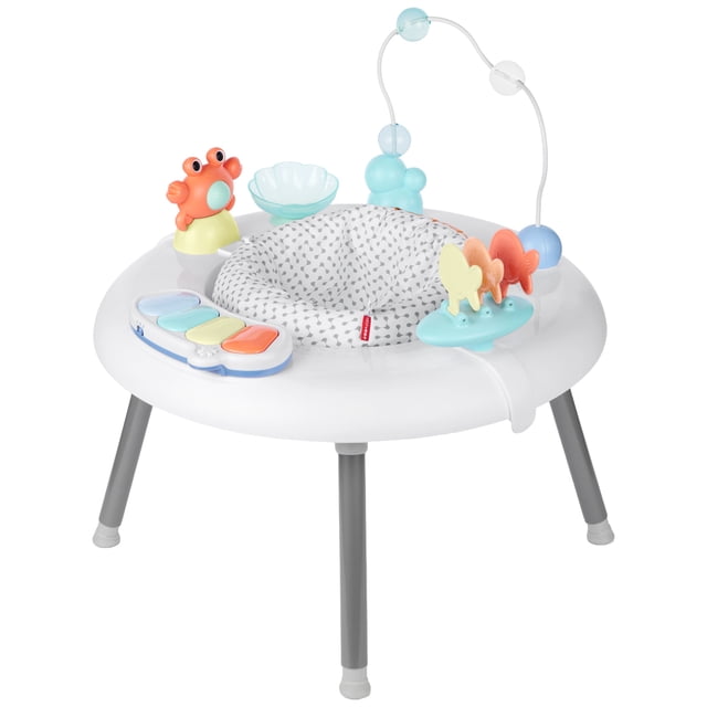 Skip Hop Seascape 2-in-1 Activity Center with a white round frame and grey legs, featuring a padded seat with a grey and white pattern. It includes interactive baby activity gym toys such as an orange crab, a blue flower-shaped bowl, a pastel piano keyboard, a blue base with yellow, orange, and red fish shapes, and a bead maze with blue and white beads.