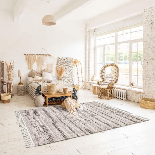 ECARPET Tapis du Sud-Ouest pour Couloir, Cuisine Aztec Collection en Gris avec Motifs Aztèques Texturés et Bords à Franges, Posé sur un Plancher de Bois Clair dans une Pièce Ensoleillée avec de Grandes Fenêtres. Ce Tapis Intérieur Présente un Endos Antidérapant et des Fils Synthétiques Durables, Idéal pour les Zones Très Passantes comme les Cuisines et les Couloirs. le Tapis Complète une Déco Rustique et Minimaliste Incluant des Meubles en Osier et une Literie Neutre.