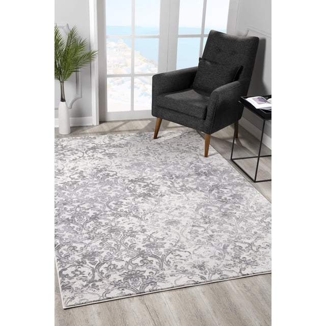 Rug Branch Oasis Collection Tapis Moderne à Motif Damassé en Gris Pâle et Blanc avec des Motifs Damassés vintage Complexes et Géométriques, Fabriqué à Partir de Fibres Durables de 80 % polyester et 20 % Coton, Placé sur un Plancher de Bois Clair à Côté d'Un Fauteuil Gris Foncé de Style Mi-Siècle Moderne avec des Pieds en Bois, une table d'Appoint en Métal Noir avec un Livre Ouvert, et un vase Blanc avec des Feuilles de Palmier Vertes Près d'Une Fenêtre avec une Vue Côtière. Idéal pour les Espaces Intérieurs à Fort Achalandage comme les Salons