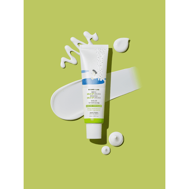 Round Lab Birch Mild-Up UVLOCK Sunscreen SPF50+ PA++++ 50ml tube with birch tree illustration on white and green packaging, set on a light green background with white sunscreen lotion swatches showing its smooth, lightweight texture suitable for daily moisturizing sun protection.