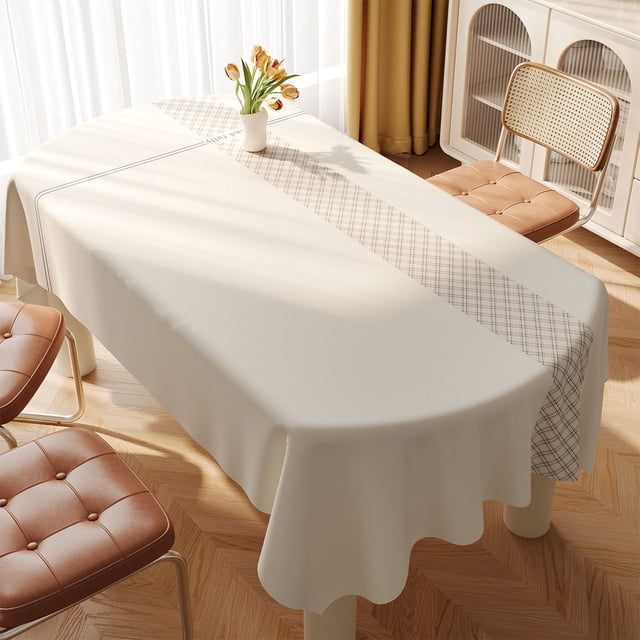 PVC Tablecloth, Rectangular Picnic Party Cloth, Waterproof Dinner Table Cover in beige, displayed on a dining table in a bright room. The tablecloth features a simple design with a subtle checkered pattern along the center, complementing the surrounding decor. Washable and easy-clean, it is suitable for dining tables, coffee tables, and office desks, offering protection against wear and tear while enhancing home aesthetics.