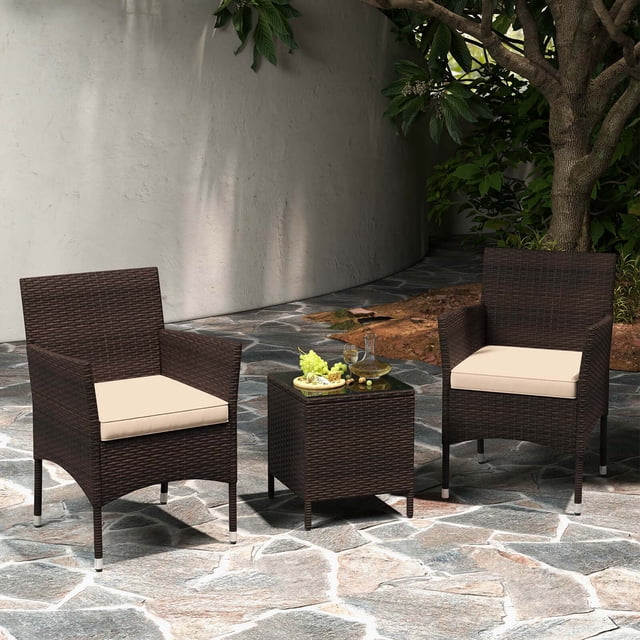 Costway Ensemble de Conversation Extérieur 3 Pcs avec Siège Coussiné et Plateau en Verre Trempé en beige. l'Ensemble Comprend Deux Chaises de patio avec Cadres en Rotin PE Brun Mélangé et Coussins de Siège Beiges, et une table Basse Carrée avec Dessus en Verre Trempé Sécurisé par Ventouses. les Chaises Dotées de Dossiers Ergonomiques et de Cadres Métalliques Robustes Pouvant Supporter jusqu'à 400 Lb Chacune. l'Ensemble Est Exposé sur un patio en Pierre Entouré de Verdure, Idéal pour la Détente en Plein Air.