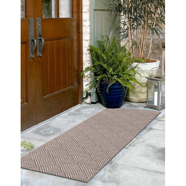 ECARPET Laura Contemporary Runner Rug with a repeating geometric pattern of overlapping pointed angles in natural beige and off-white tones, made from stain-resistant polypropylene fibers, placed on a stone floor outside wooden double doors with potted green plants and a metal lantern, suitable for indoor and outdoor use.