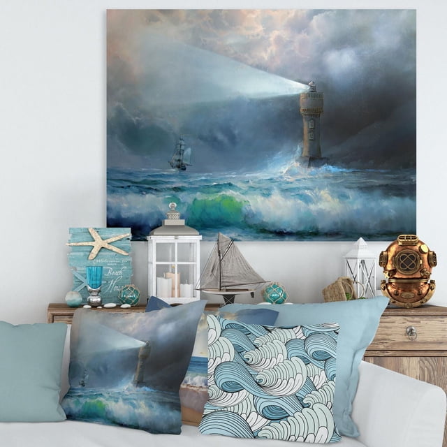 Designart Lighthouse Shining Light During Stormy Night II Canvas Wall Art depicts a stormy ocean with a lighthouse casting a bright beam over turbulent blue and green waves and a distant sailing ship, printed on premium cotton canvas with gallery-wrapped edges, ideal for nautical-themed home décor.
