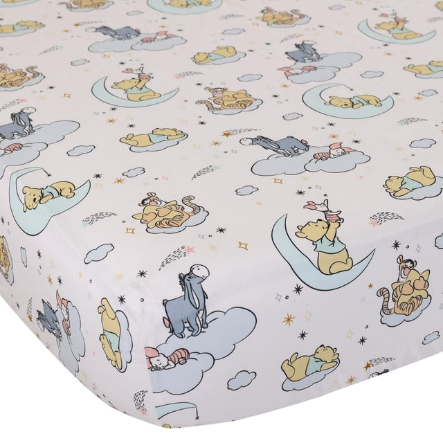 Disney Fitted Crib Sheet made from soft breathable cotton, featuring pastel illustrations of Winnie the Pooh, Piglet, Tigger, and Eeyore on clouds and crescent moons, sized 28 by 52 inches with 8-inch depth to fit standard crib mattresses.