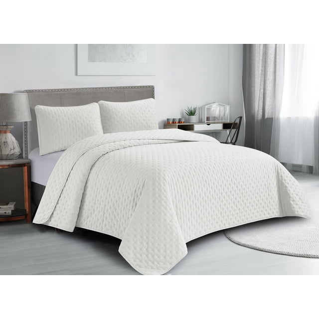 Lightweight, hypoallergenic white pinsonic quilt set with matching pillows displayed on a bed in a bright, minimalist bedroom.