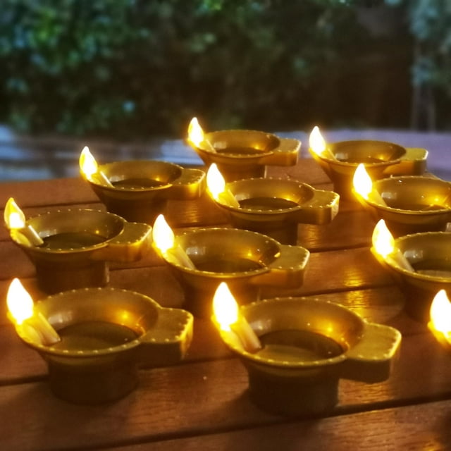 Diwa Li Lampe à Huile Sans Flamme à Détection d'Eau à DEL Dorée en Forme de Chauffe-Plat pour la Maison, Mettant en Valeur un Ensemble de Bougies Sans Flamme de Couleur Or avec des Flammes DEL Réalistes. Conçues sous une Forme de Lampe à Huile Traditionnelle, Ces Chauffe-Plats Sont Disposés sur une surface en Bois, Parfaits pour la Déco de la Maison, les Cérémonies de pooja, les Événements de Pendaison de Crémaillère et les occasions Festives. Doté d'Une Technologie Avancée de Détection d'Eau pour un Fonctionnement