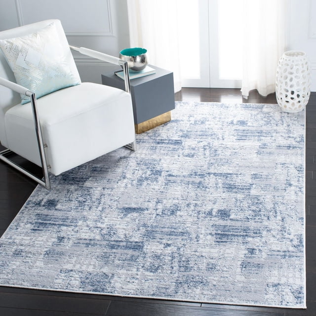 Safavieh Amelia Carrie Tapis Abstrait Usé Présentant une texture de Fil Synthétique Pelucheuse avec un Motif Abstrait Bleu et Gris, Posé sur un Plancher de Bois Franc Foncé dans une Pièce Contemporaine avec un Fauteuil Blanc et une table d'Appoint Grise, Idéal pour les Espaces de Vie Modernes Ou les Chambres.