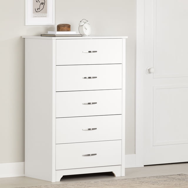 South Shore Fusion 5-Drawer Chest for Adult in pure white, tall and narrow with five smooth metal slide drawers featuring slim metal handles, curved cutout base, and decorative moldings on drawer sides, suitable for bedroom storage and organizing clothes, shown with books, a wooden box, and a white alarm clock on top in a neutral room.