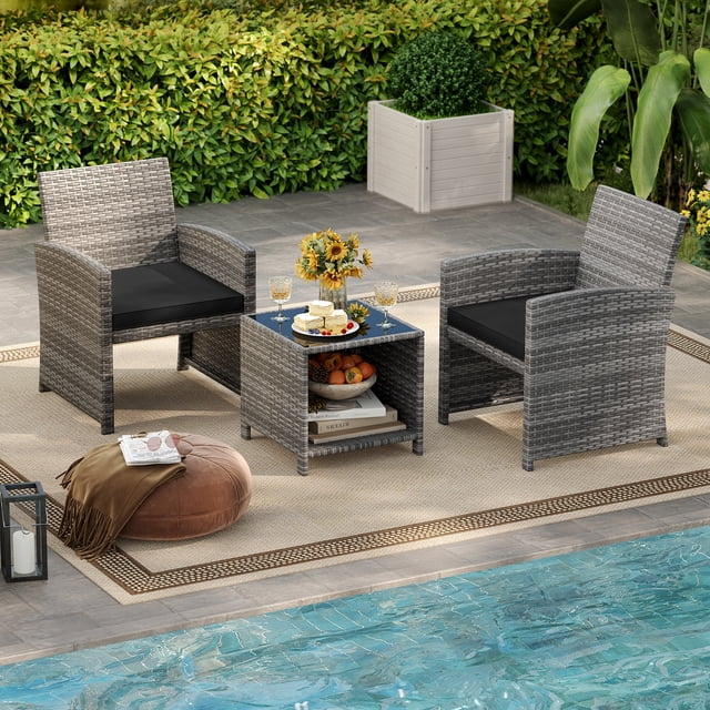 Gymax 3 Pieces Patio Furniture Set PE Rattan Chairs Set w/ Storage Coffee Table in black, featuring two mix gray PE rattan chairs with black cushions and a matching coffee table with a tempered glass top and open storage shelf. The set is displayed in an outdoor patio setting near a pool, surrounded by greenery and decorative elements like a pouf and lantern.