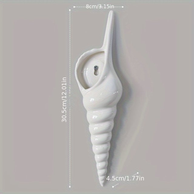 1pc three-dimensional seashell vase designed as a minimalist wall decoration pendant. This ceramic wall vase features an irregular, coastal-inspired shape resembling a seashell, with a glossy white finish. Measuring approximately 30.5 cm (12.01 inches) in height, 8 cm (3.15 inches) in width, and 4.5 cm (1.77 inches) in depth, it includes a built-in plant stand and is suitable for both indoor and outdoor use. The vase is mounted on a neutral-coloured wall, showcasing its decorative and functional appeal.
