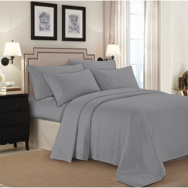 Johnson Home 500 Thread Count Certified Organic Cotton Sheet Sets in grey, displayed on a bed with a beige upholstered headboard with nailhead trim. The set includes fitted and flat sheets plus pillowcases, styled in a softly lit bedroom with cream walls, two framed architectural prints, wall sconces, and a black nightstand. The breathable organic cotton provides softness, durability, and year-round comfort.