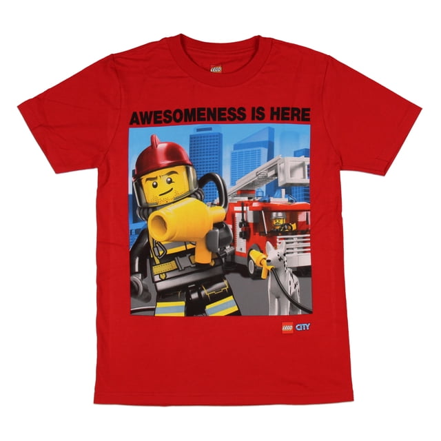 Lego City Boy's Awesomeness Is Here Fire Rescue T-Shirt red boys' short-sleeve 100% cotton tee, flat front-facing view with a fire rescue chest print featuring a yellow fire truck and firefighter minifigure and white text 'Awesomeness is Here'; visible crew neckline and tagless collar, laid on a neutral background, often chosen for everyday play and Lego-themed outfits.