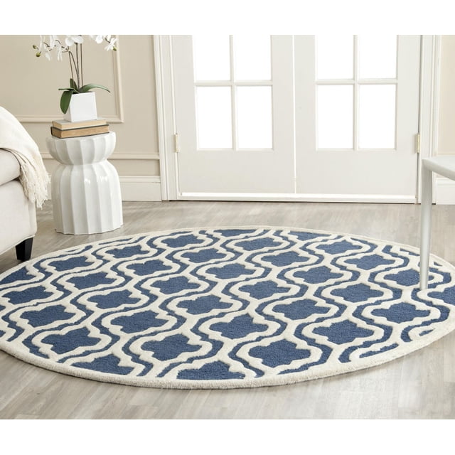 Safavieh Cambridge Kirsten Geometric Area Rug, round with blue and white geometric pattern, hand-tufted wool featuring plush cut and high/low loop piles, placed on light wood flooring in a bright room with white French doors, ideal for home or office accent.