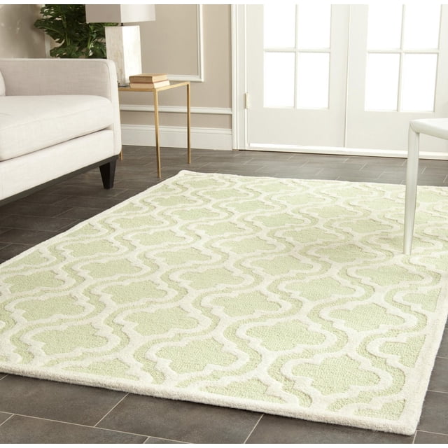 Safavieh Cambridge Kirsten Geometric Area Rug with hand-tufted wool in light green and cream featuring a raised geometric trellis pattern, shown on dark tile flooring in a living room with beige sofa and gold side table, suitable for enhancing home or office decor with durable texture.