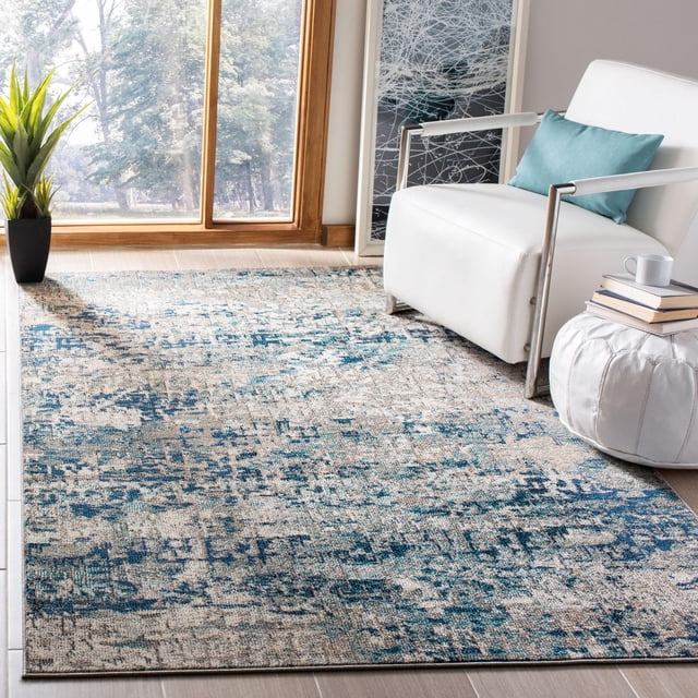 SAFAVIEH Madison Kebo Tapis Vintage Abstrait pour Aire avec un Motif Abstrait Vintage Tissé Mécaniquement dans des Tons Bleu et beige, Placé sur un Plancher de Carreaux dans une Pièce Ensoleillée. le Tapis Est à Côté d'Un Fauteuil Blanc avec un Coussin Bleu, un pouf Blanc Tenant des Livres et une Tasse, et une Plante en Pot Près d'Une Grande Fenêtre, Convenant à la Déco Intérieure Transitionnelle et à l'Utilisation comme Tapis d'Accent.