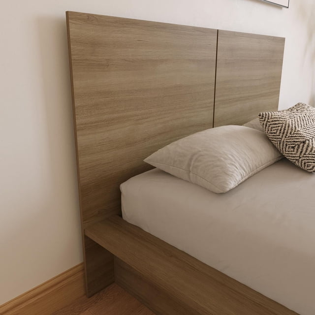 Nexera Tête de Lit James en Fini Chêne Brun Pâle au design Minimaliste et Moderne, Montrée Orientée vers l'Avant, Attachée à un Cadre de Lit Sans Sommier, aux Lignes Épurées et à la texture Naturelle de grain de Bois, Assortie à une Literie beige et à un Coussin à Motifs dans un Cadre de Chambre Neutre.