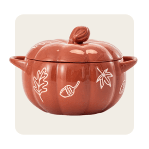 A ceramic soup tureen shaped like a pumpkin, with a lid and handles, decorated with white autumn leaf and acorn illustrations.