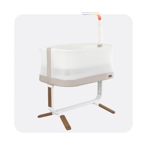 Modern white and beige baby bassinet with mesh sides and a built-in overhead light on a sturdy frame.