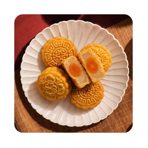 A white plate with four traditional mooncakes, one of which is cut in half to show a golden yolk filling inside. The mooncakes have intricate patterns on top and are arranged neatly on the plate.