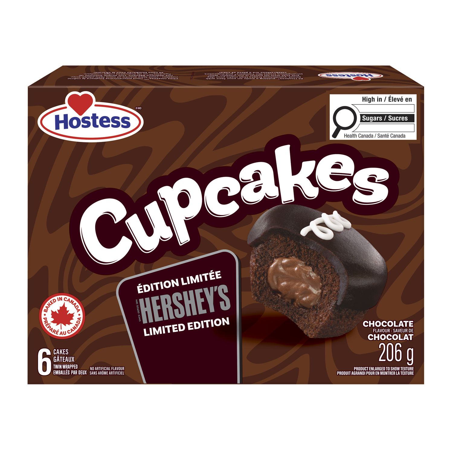 Hostess® Hershey's® Petits Gâteaux Aromatisés au Chocolat Vue de studio en Face d'Un Paquet Familial de Six avec des Gâteaux Collation au Chocolat Emballés en Double; un Gâteau Coupé Ouvrant pour Montrer le centre Crémeux Aromatisé au Chocolat, Chacun Surmonté de l'Extérieur de Gâteau Blanc Hostess® Gigoteux et Brun Foncé visible, Emballage de Marque en Arrière-Plan, Présenté pour Boîte à Lunch Ou Collation sur le Pouce au Canada.