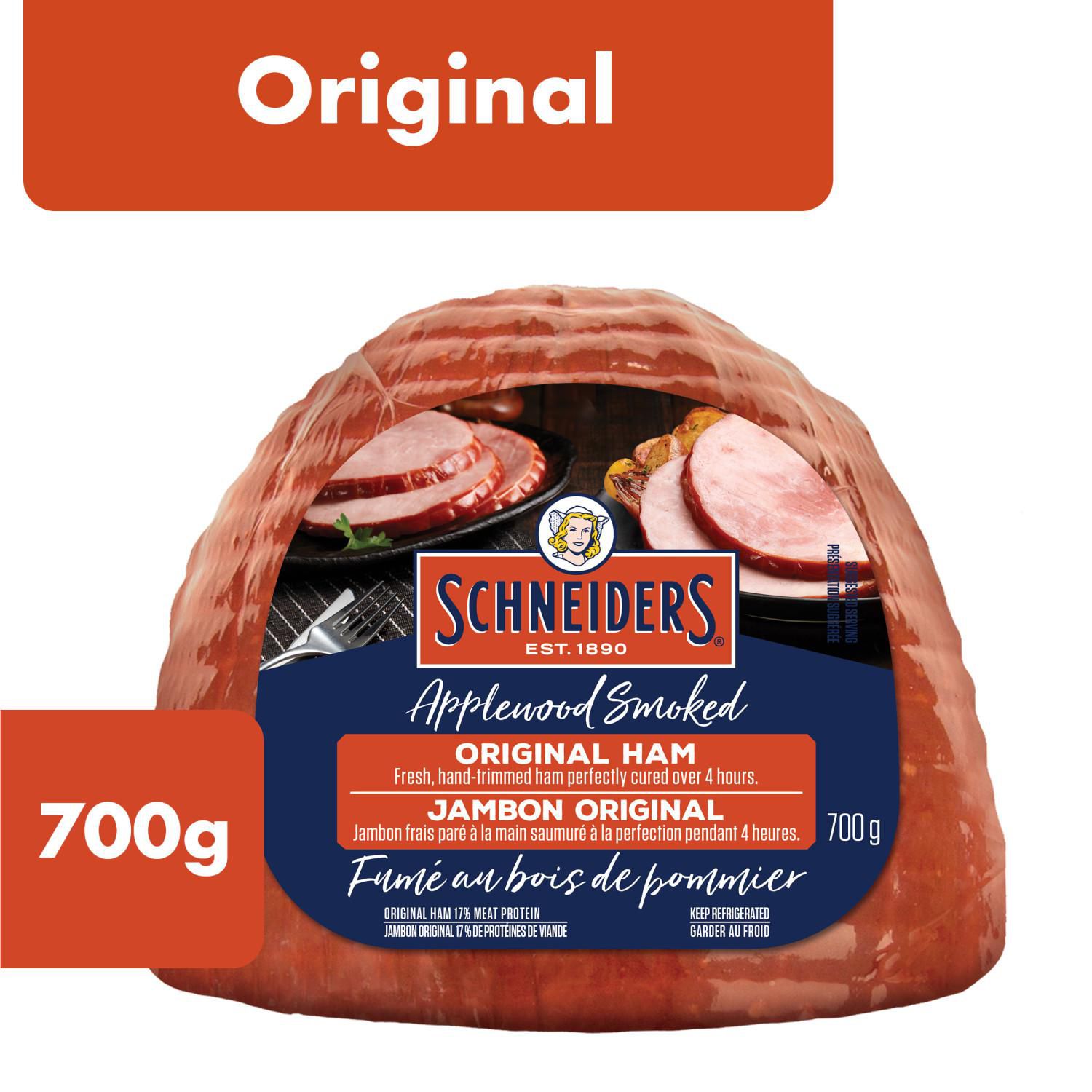 Schneiders Original Half Ham, 700 g unsliced boneless smoked ham shown whole on a cutting board with cured glaze and visible meat grain, ideal sliced for sandwiches or cubed for salads; often used cubed on charcuterie boards.